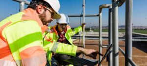 Engineers working on water treatment plant with laptop and measuring sensors