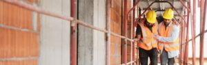 People working in construction site. Young men at work in new house inside apartment building. Latino manual worker helping injured co-worker after accident on duty
