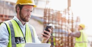 Construction worker digital tablet texting cell phone at constru