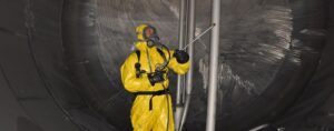 man in chemical suit PPE sprays chemical hazard on wall