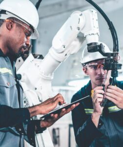 Factory workers working with adept robotic arm in a workshop . Industry robot programming software for automated manufacturing technology .